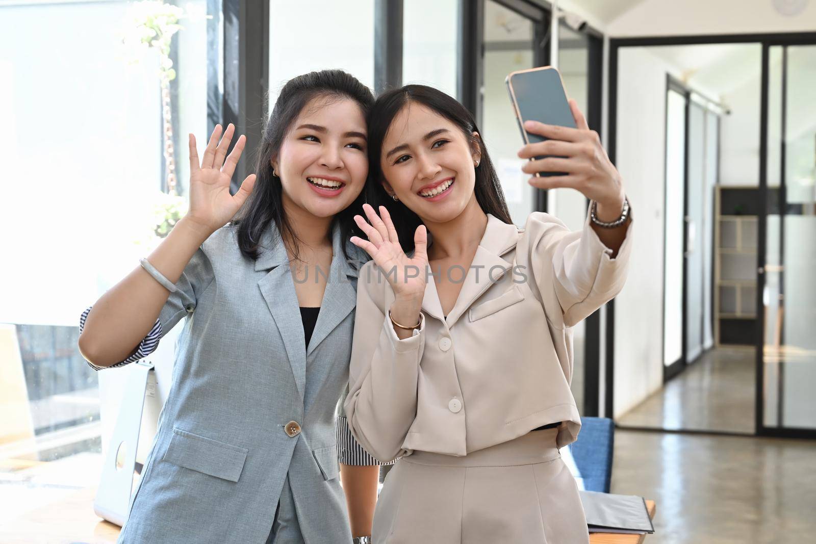 Two young women taking selfie with smartphone. by prathanchorruangsak