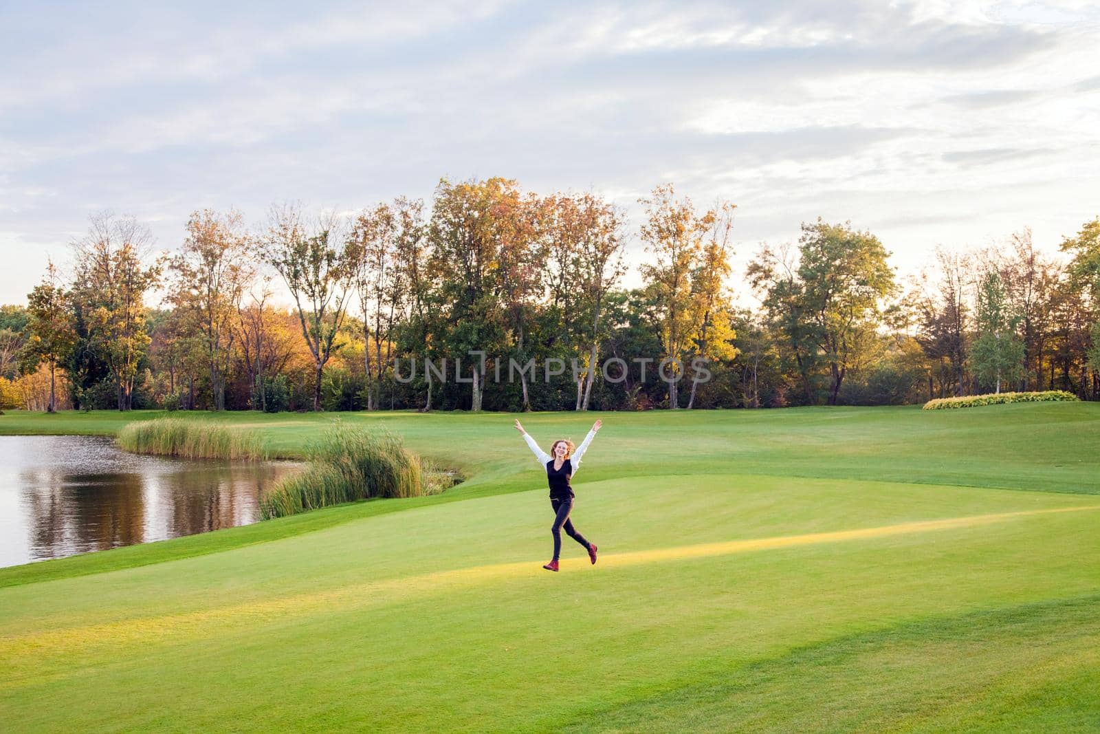 Girl runs on the green grass of the golf course. The girl happiness. Outdoor shot