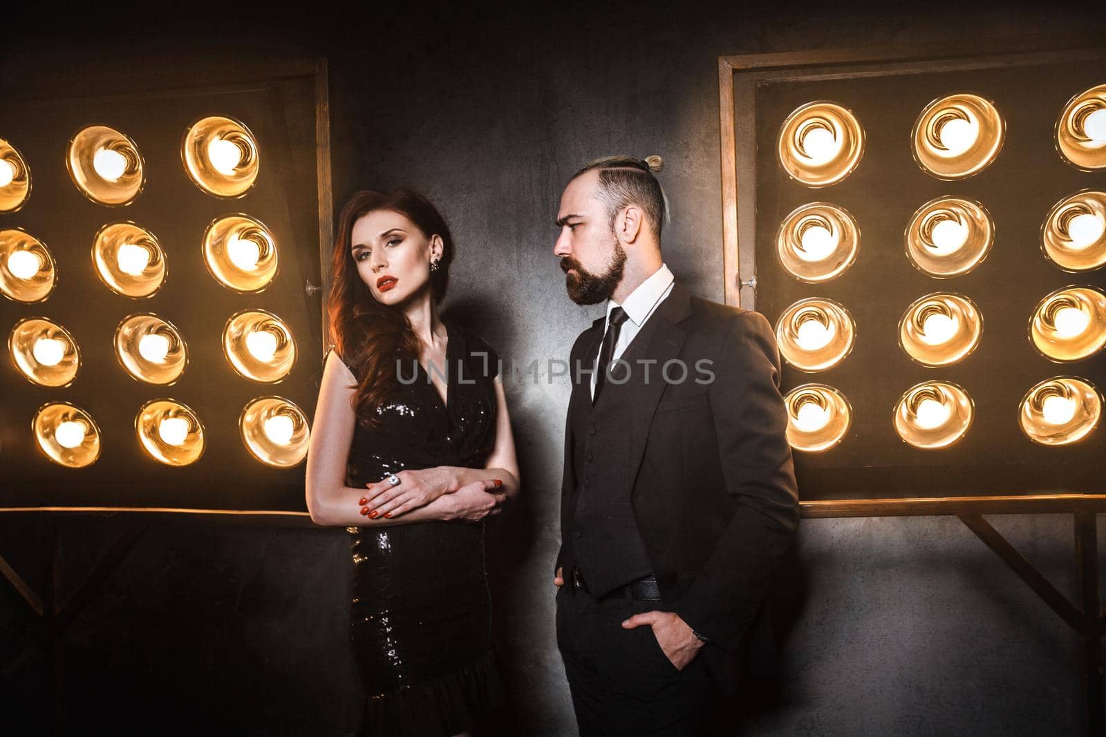 Two beautiful friends wearing elegance, standing near stage. Studio shot