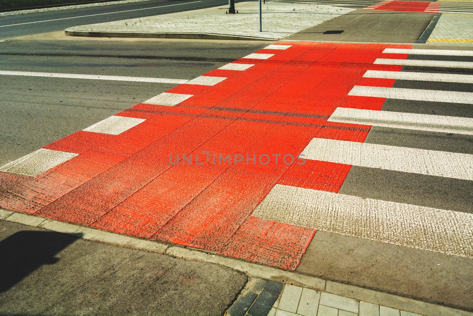 Red bike lane next to pedestrian crossing, spring day