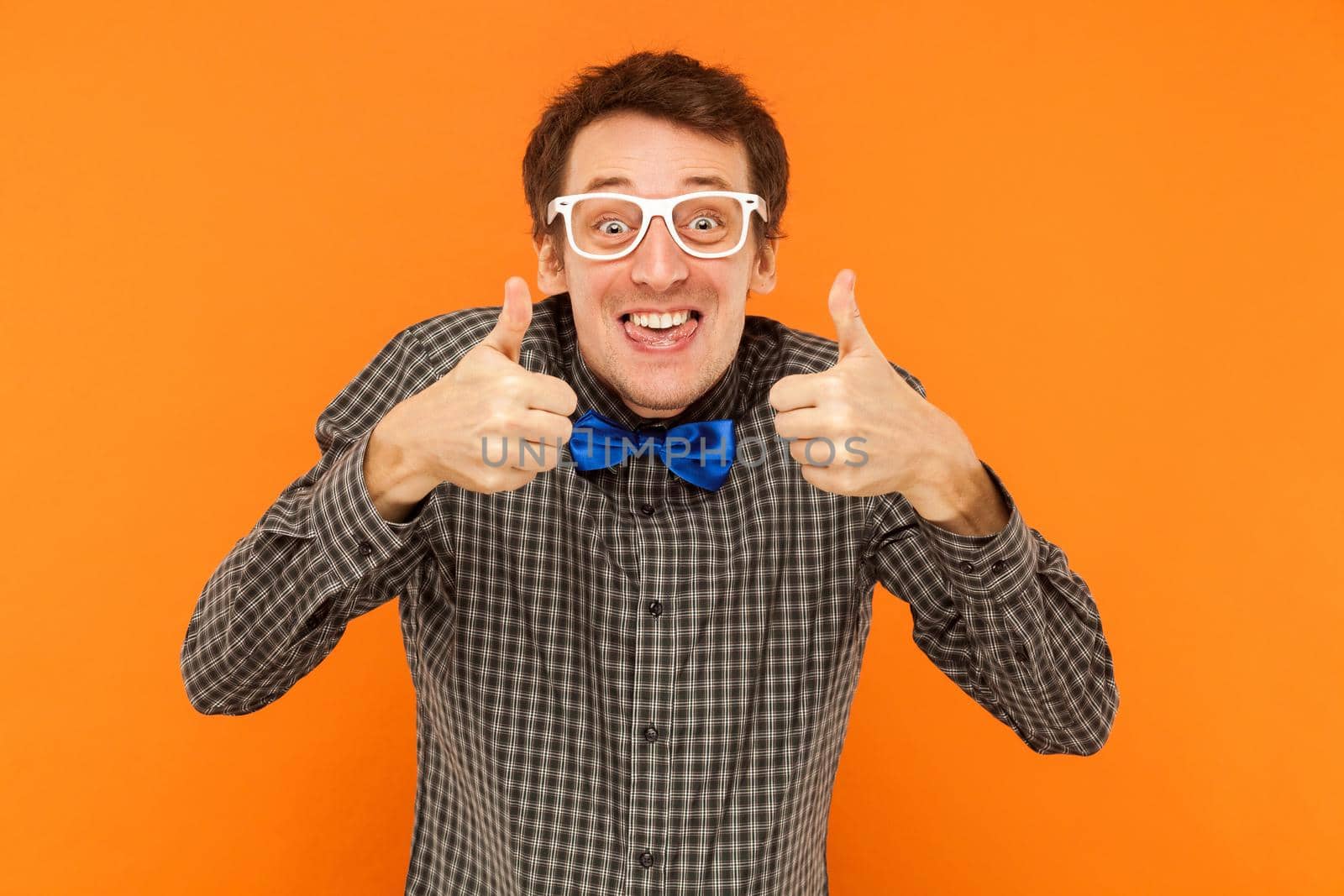 Crazy scentist tongue out and thumbs up. Studio shot. Isolated on orange background