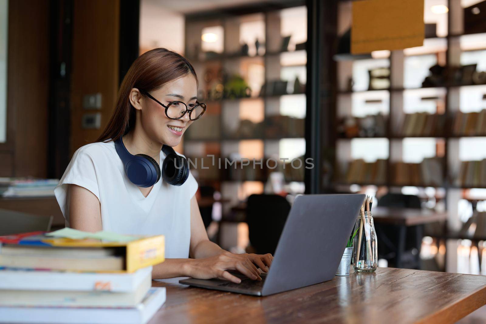 Smiling asian teenage using headset looking at laptop screen listen and learning online courses. Happy chinese business woman with headphones video call. online education concept