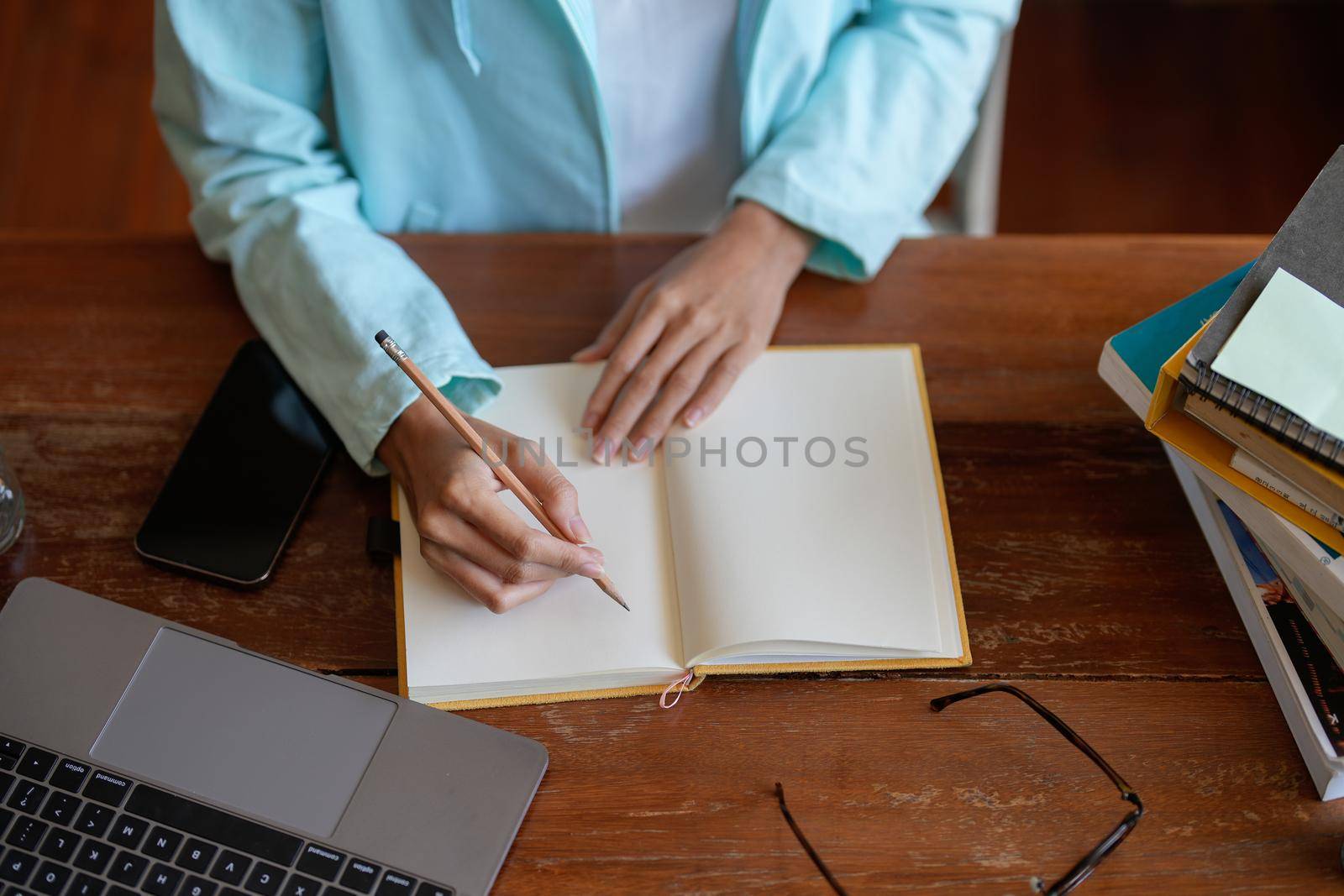 Top view shot of woman writing making list taking notes in notepad working or learning on laptop indoors- educational course or training, seminar, education online concept