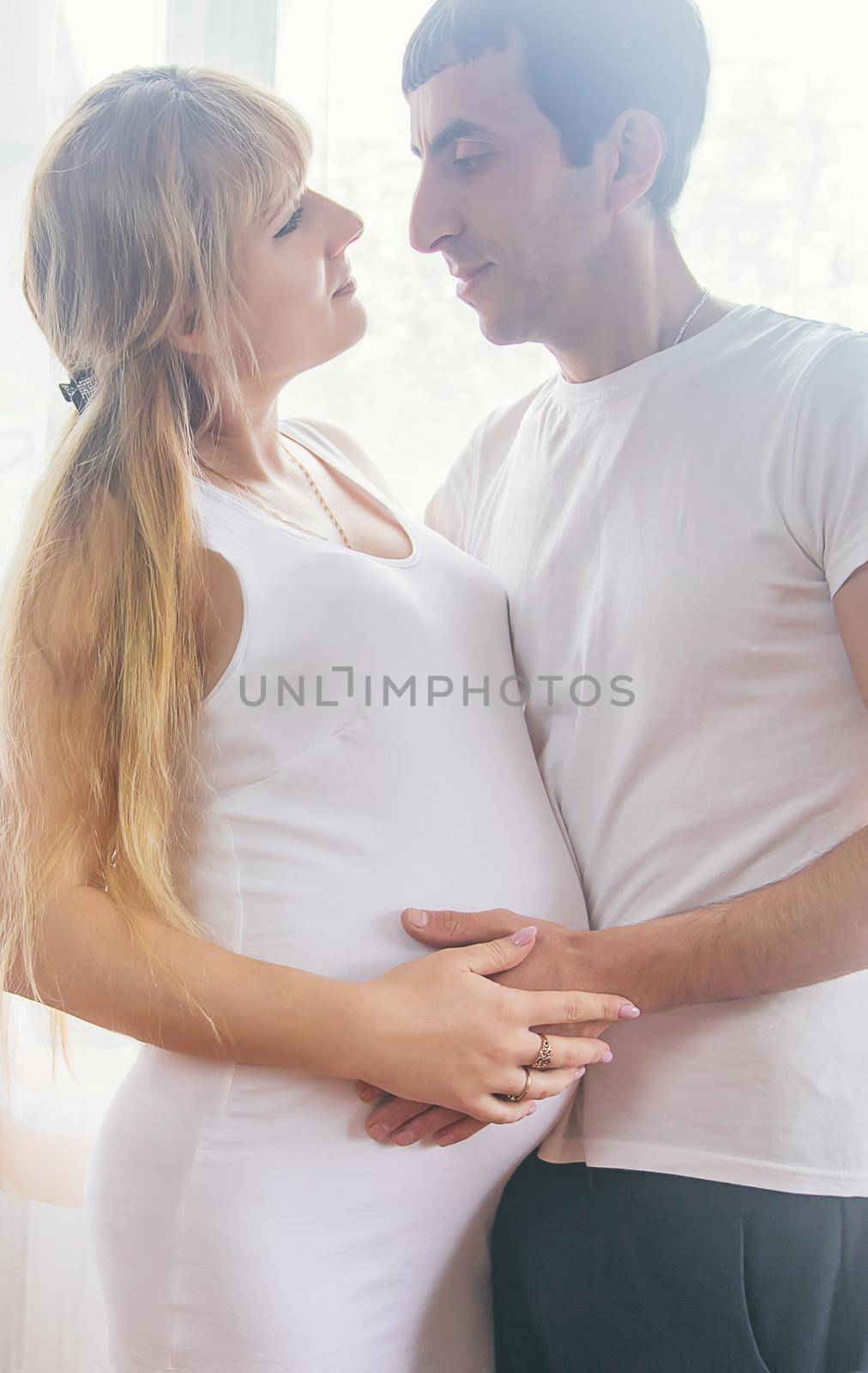 A pregnant woman and a father of a child hug a belly. Selective focus. by yanadjana