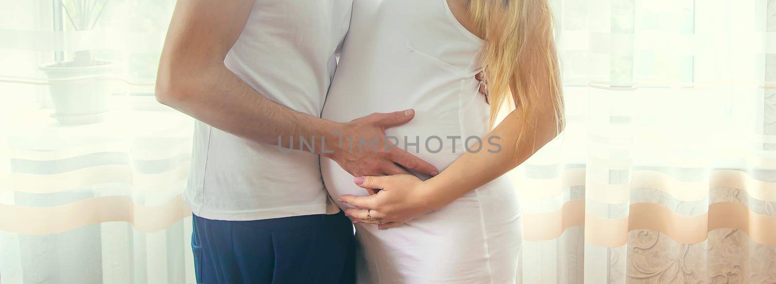 A pregnant woman and a father of a child hug a belly. Selective focus. NATURE.