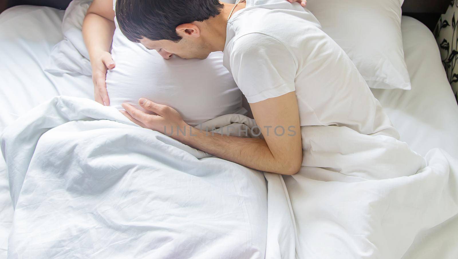 Pregnant woman with man hug belly in bed. Selective focus. people.