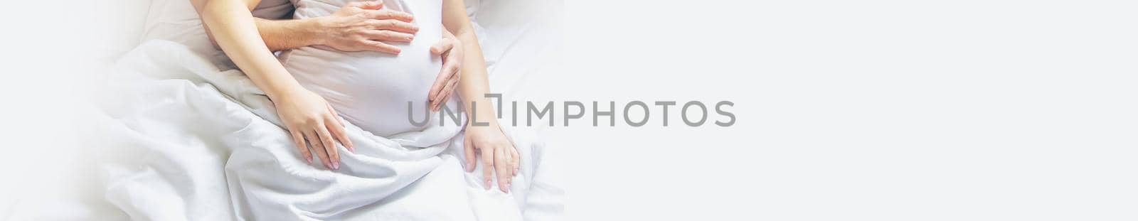 Pregnant woman with man hug belly in bed. Selective focus. people.