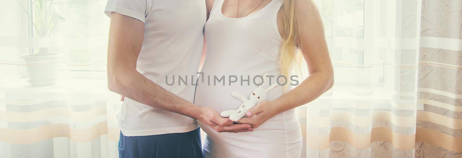 Pregnant woman with man hold toy hug belly. Selective focus. by yanadjana