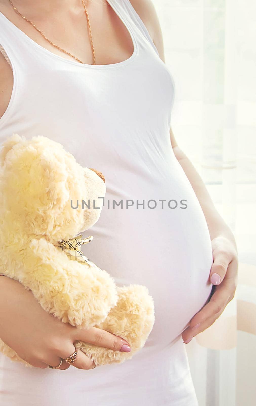 A pregnant woman with a toy hugs her stomach. Selective focus. People.