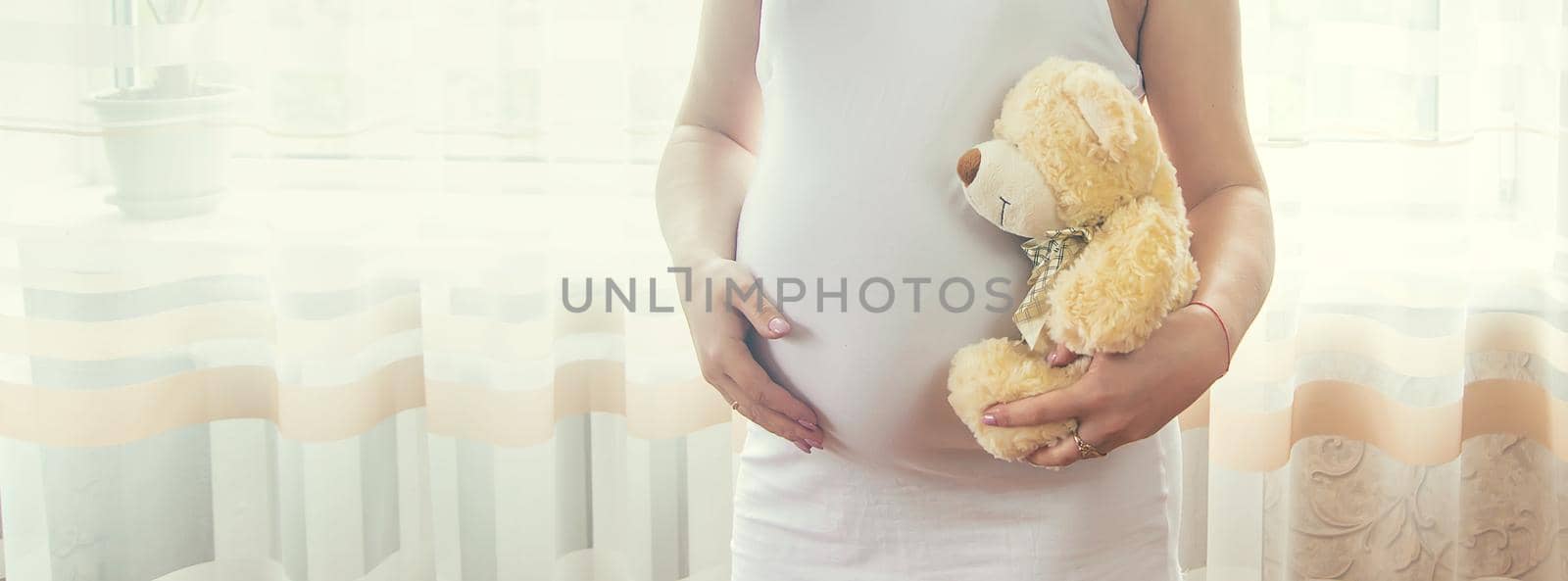 A pregnant woman with a toy hugs her stomach. Selective focus. People.