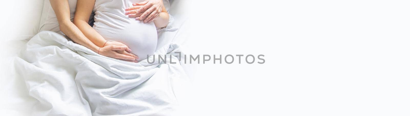 Pregnant woman with man hug belly in bed. Selective focus. people.