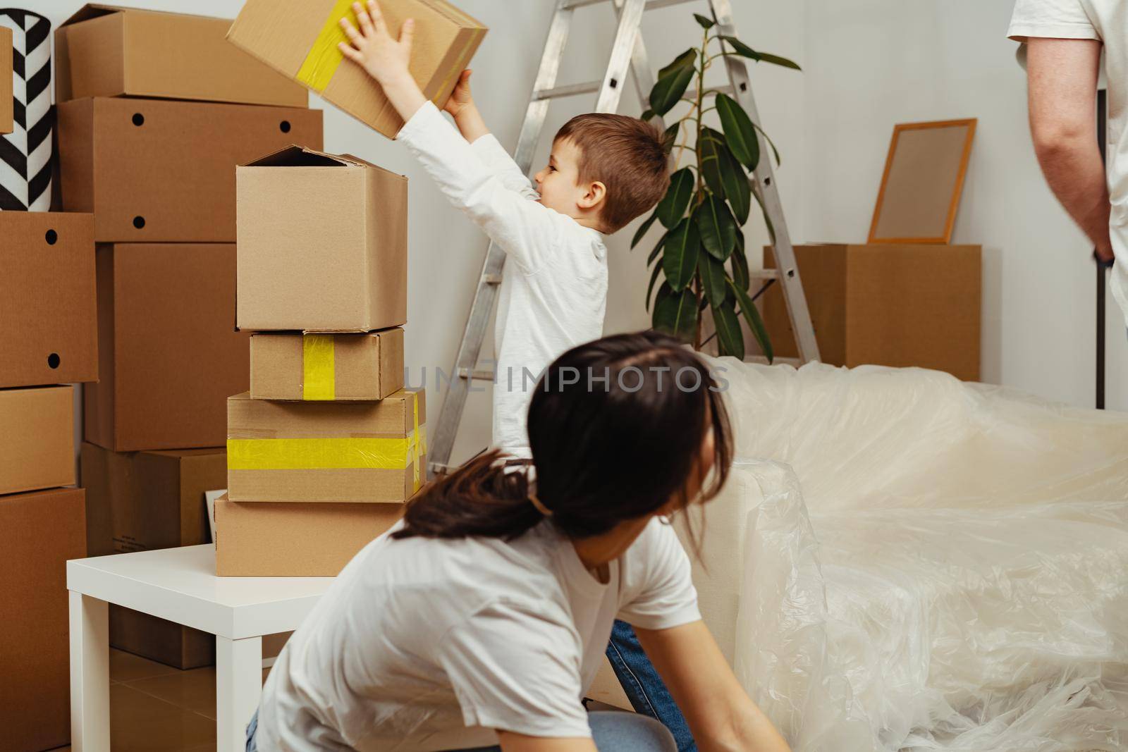 Beautiful smiling woman and little boy with cardboard boxes moving to new home, close up
