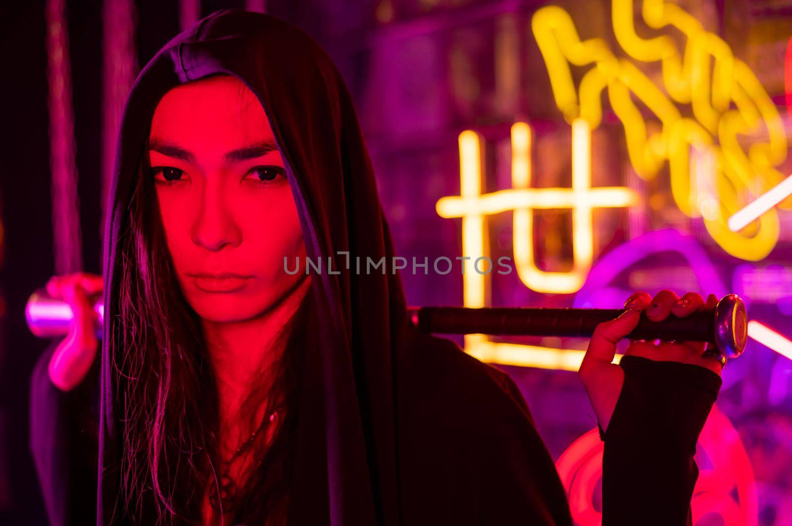 Portrait of an asian man holding a bat in a neon studio