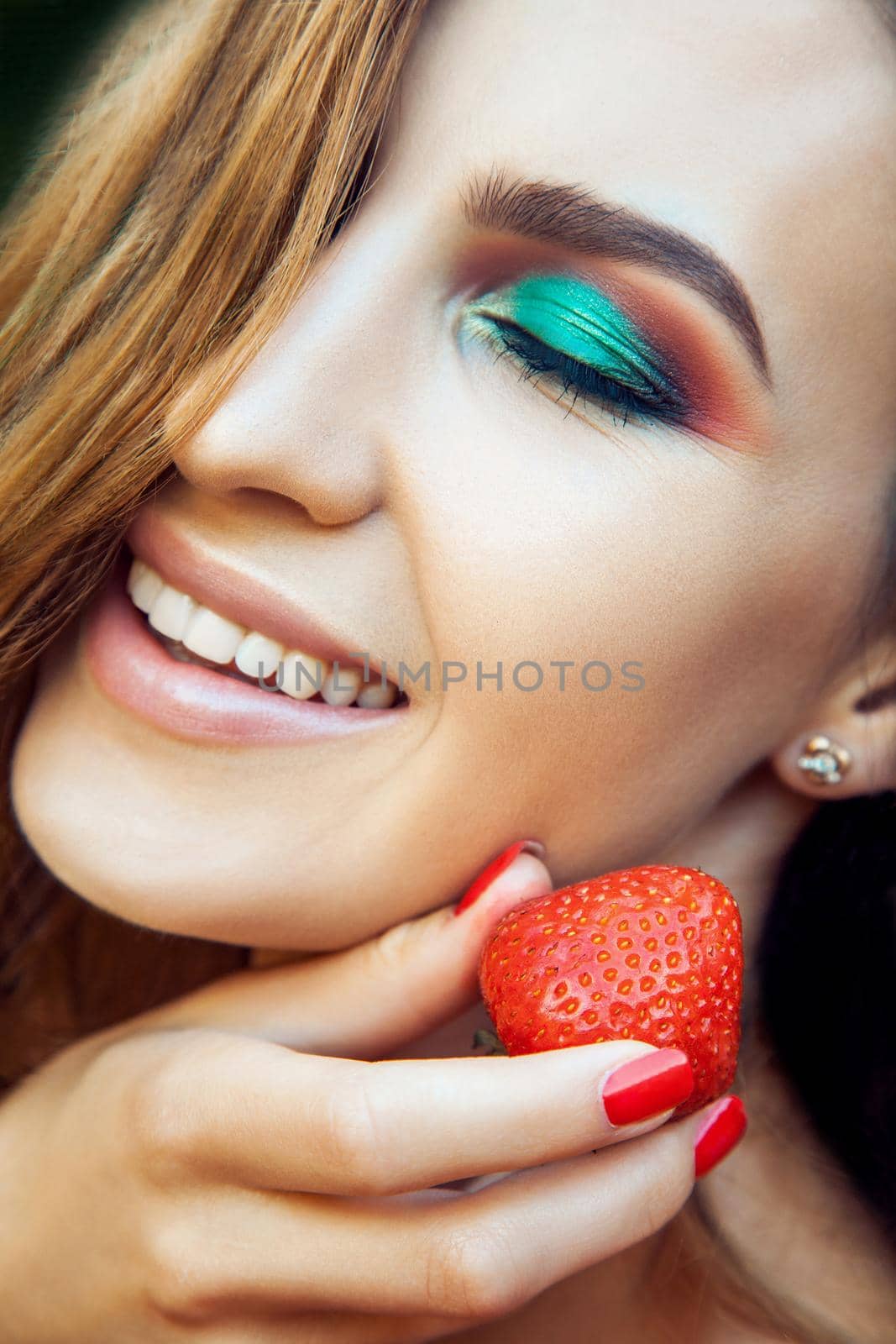 Young beautiful happy funny girl with red dress and makeup holding strawberry in summertime in the park. by Khosro1