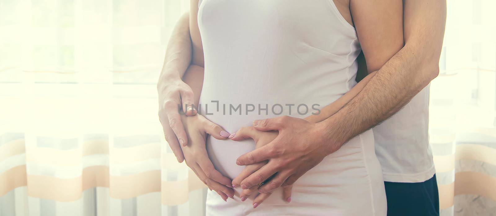 A pregnant woman and a father of a child hug a belly. Selective focus. NATURE.