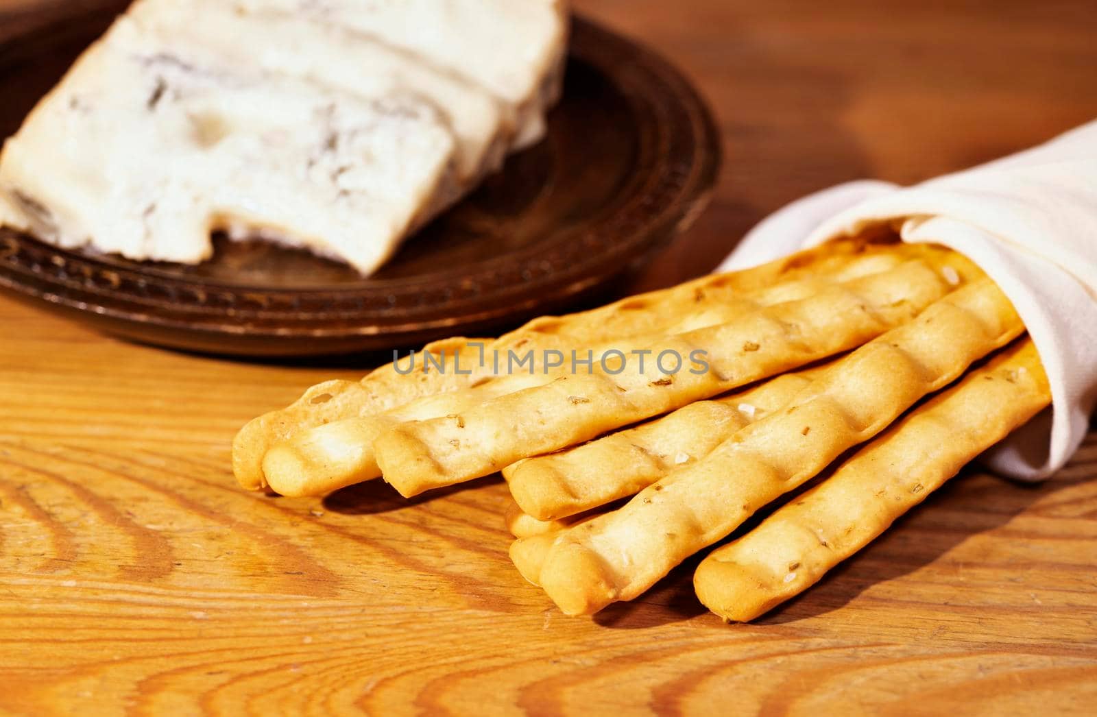 Breadsticks in white napkin and gorgonzola cheese on plate , ready to eat