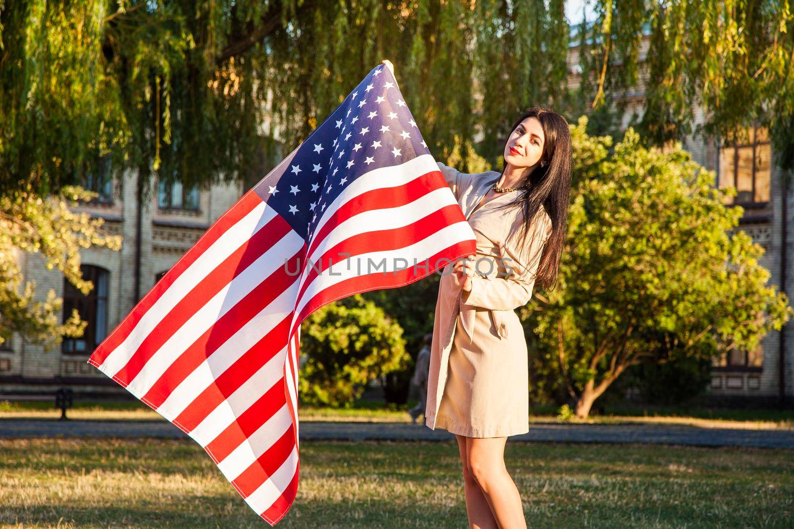 Beautiful happy woman with American flag celebrating independence day.