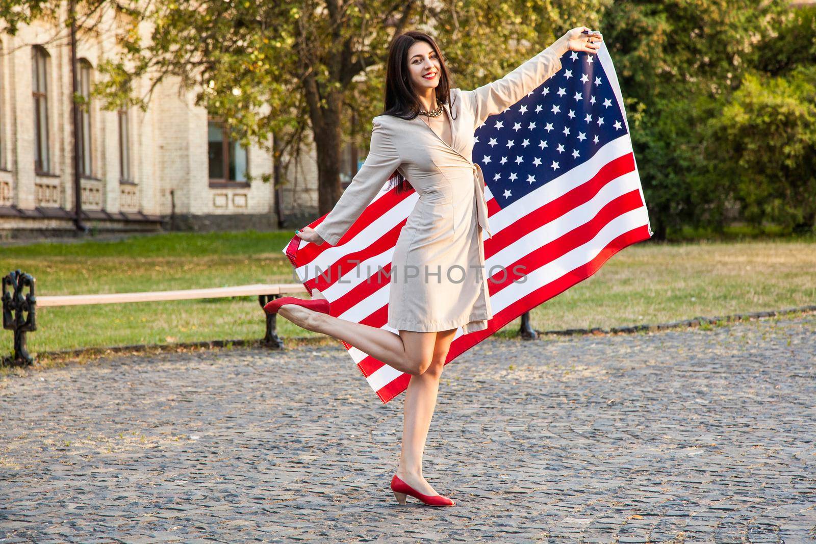 Beautiful happy woman with American flag celebrating independence day.