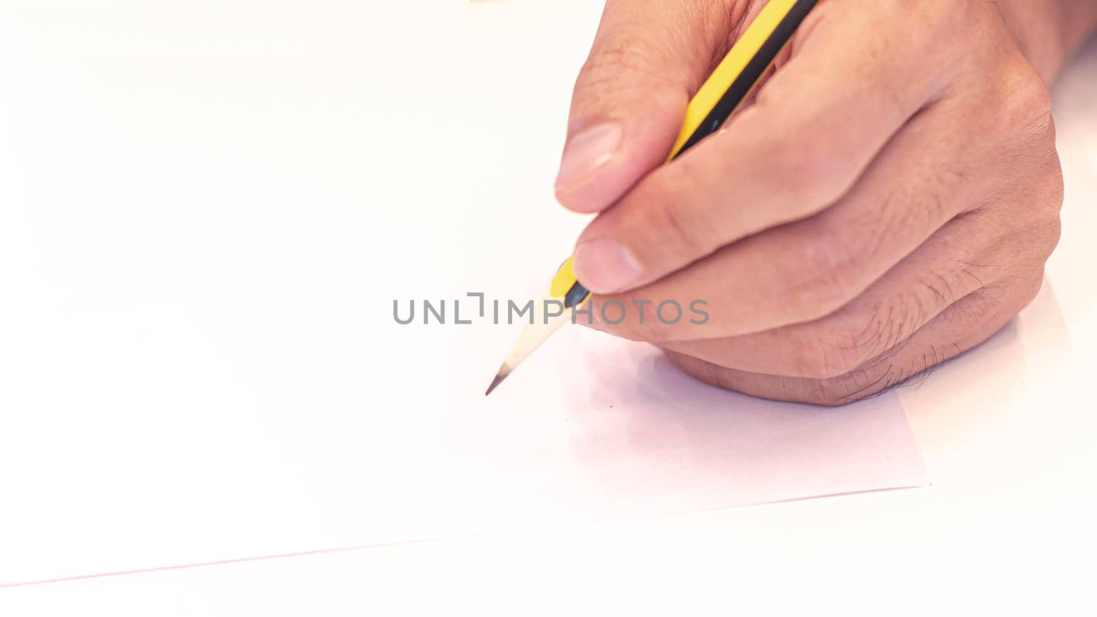 hand holding a pencil isolated on white background . Close Up on a man's hand writing on paper with a pencil  .Planning business idea background . leave note or message concept. by Petrichor