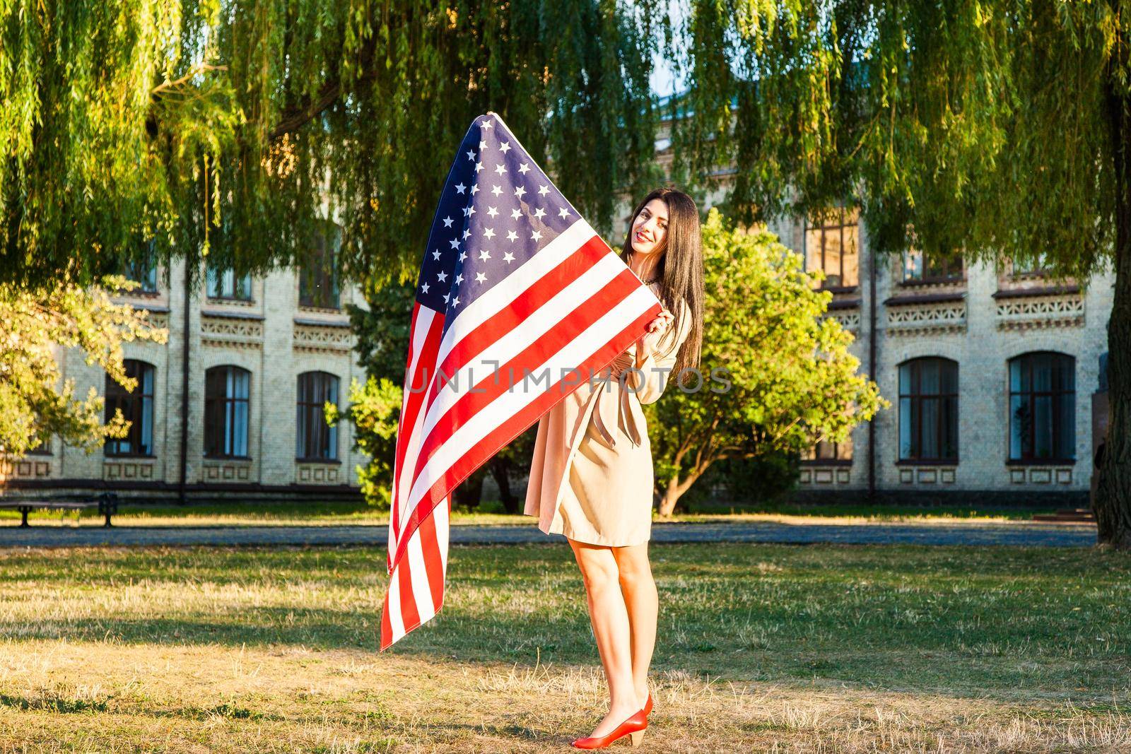 Beautiful happy woman with American flag celebrating independence day.