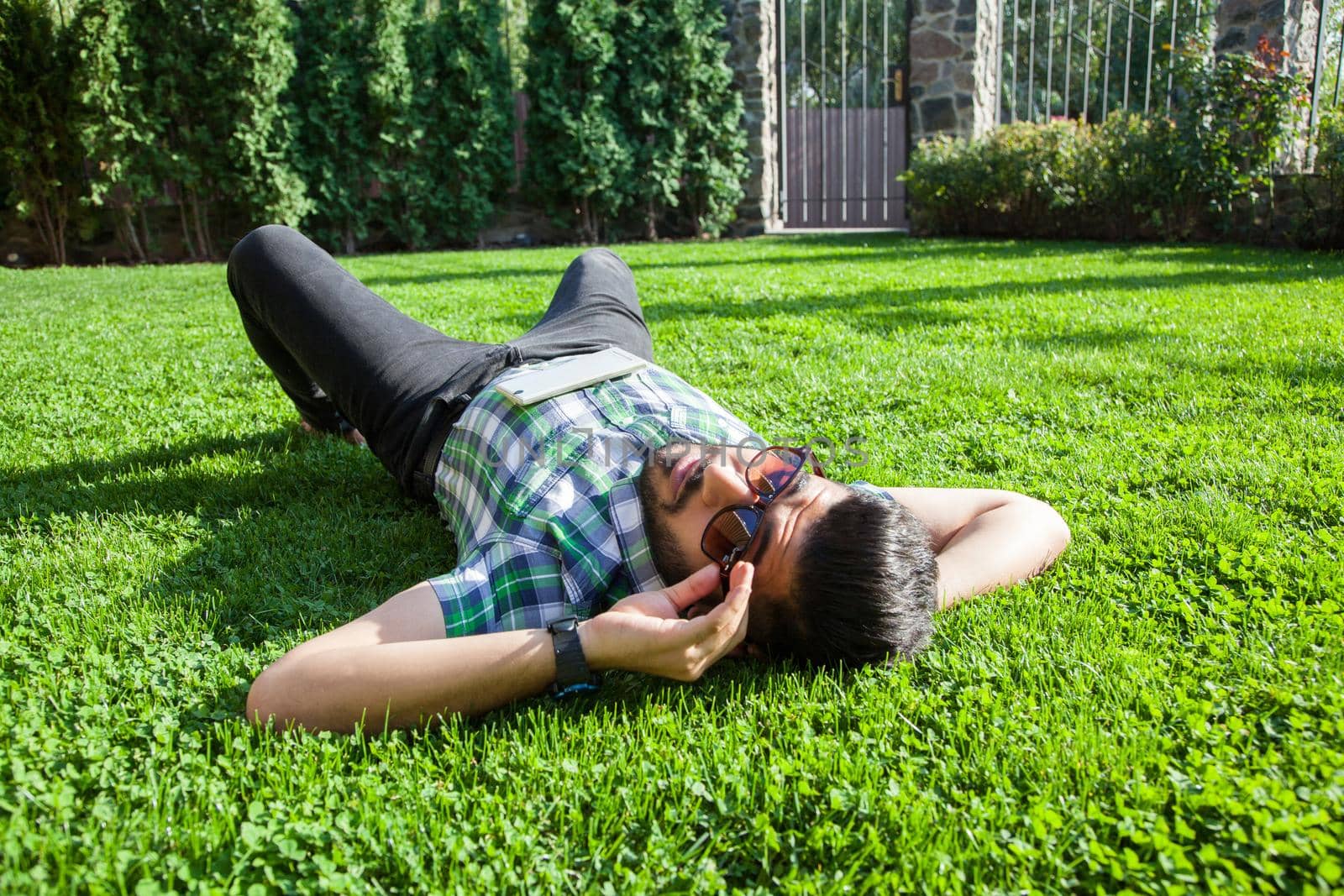 young man lie down on lawn and enjoying summertime. by Khosro1