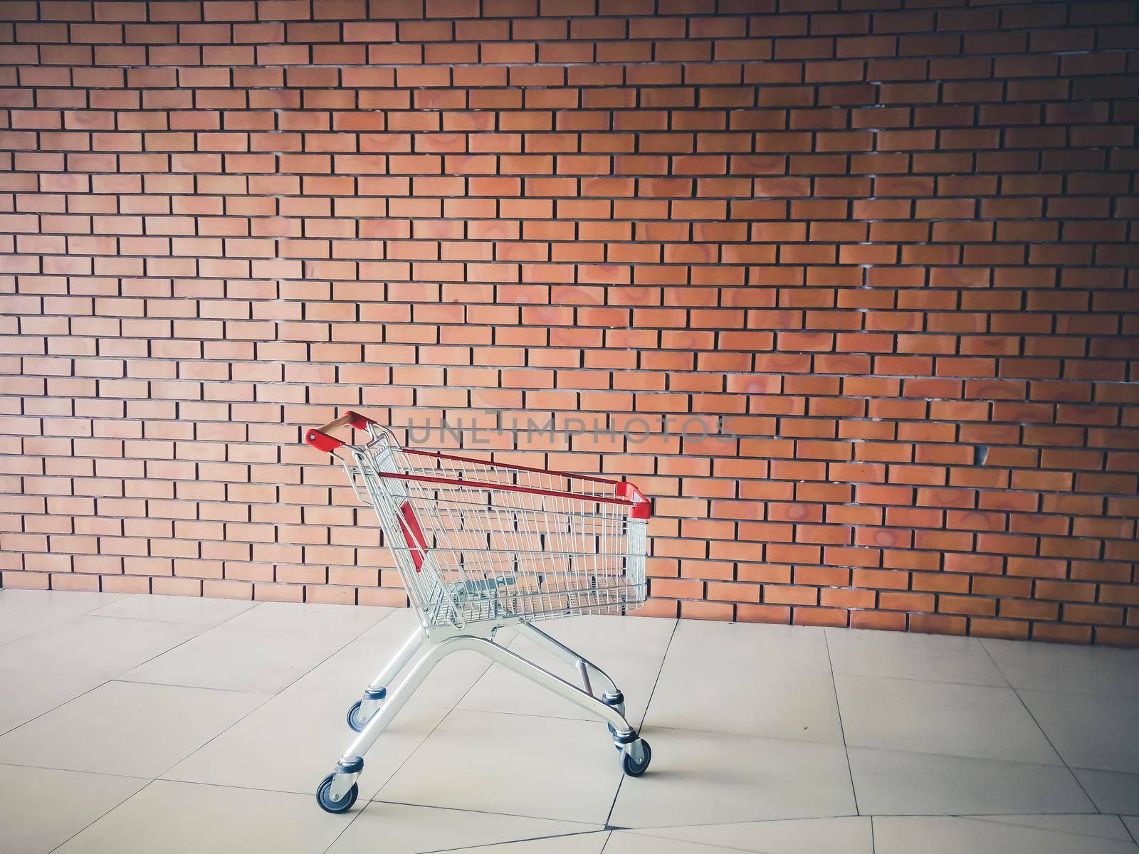 Empty shopping cart near brick wall . Shopping supermarket cart. Shopping time concept idea