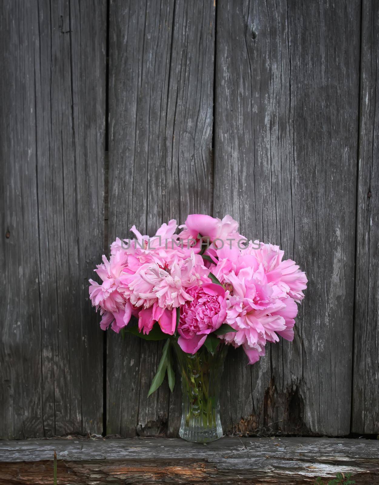 Bouquet of peony flowers on a wooden bench outdoors
