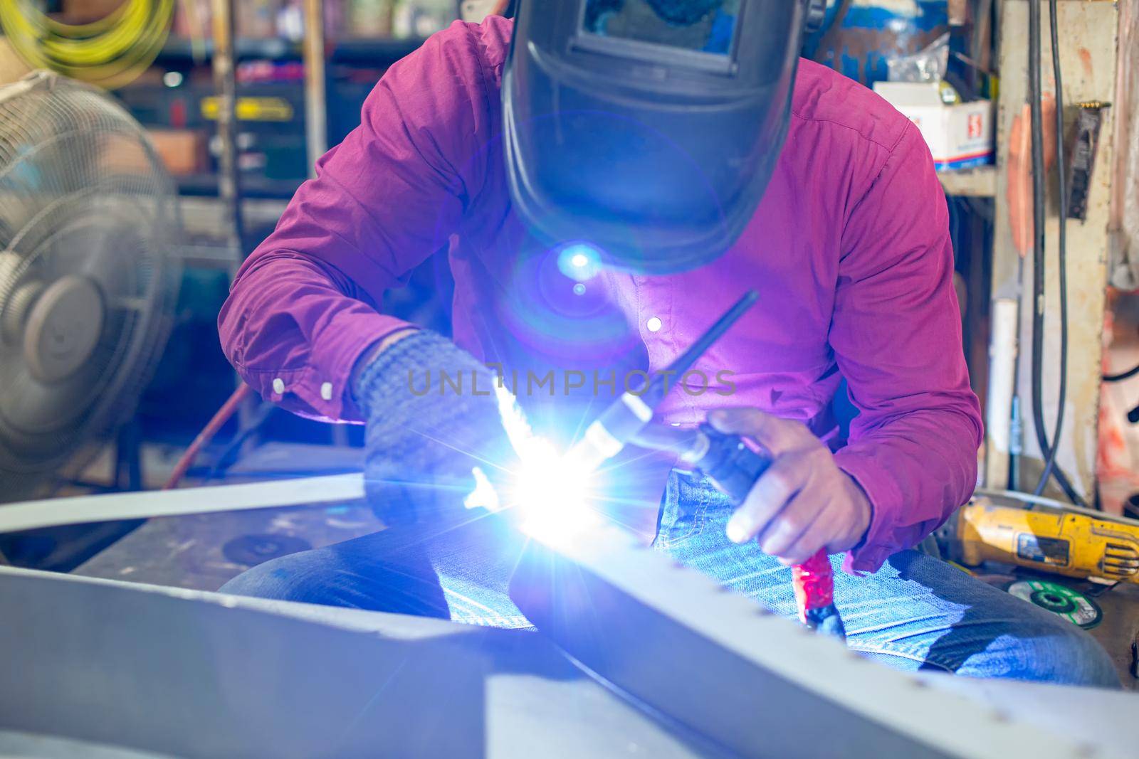 Welder used grinding stone on steel in factory with sparks, Welding process at the industrial workshop, hands with instrument in frame.