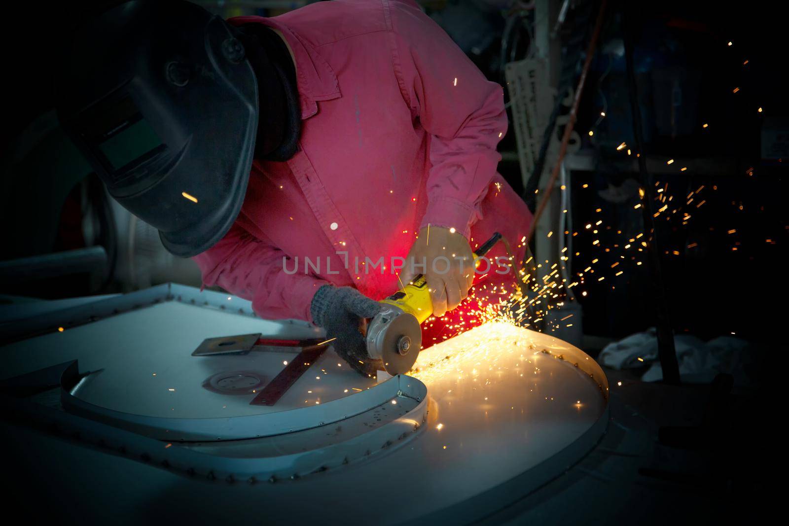 Welder used grinding stone on steel in factory with sparks, Welding process at the industrial workshop, hands with instrument in frame.