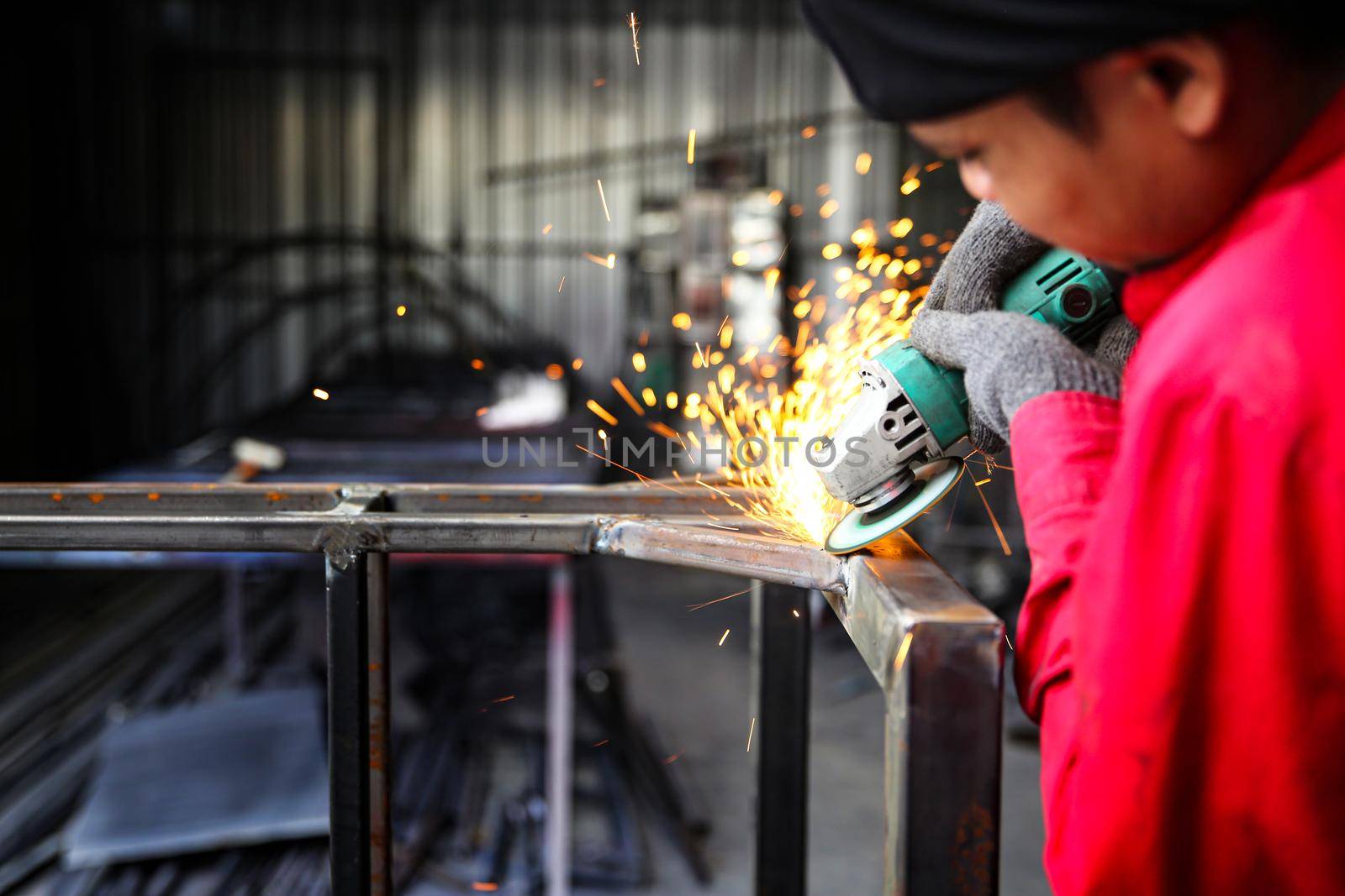 Welder used grinding stone on steel in factory with sparks, Welding process at the industrial workshop, hands with instrument in frame. by chuanchai