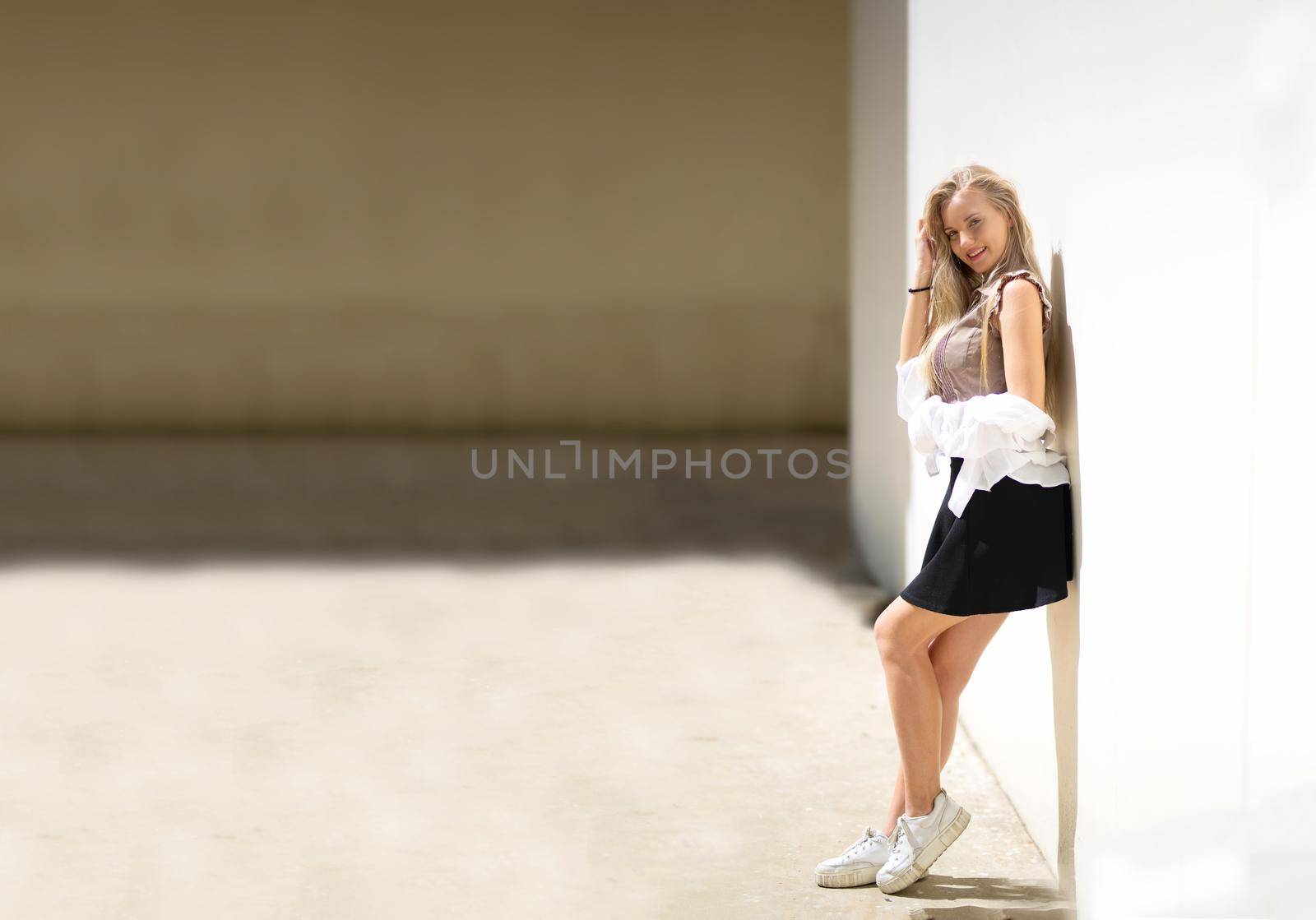 Portrait of young beautiful woman blonde hair standing against wall with copy space by chuanchai