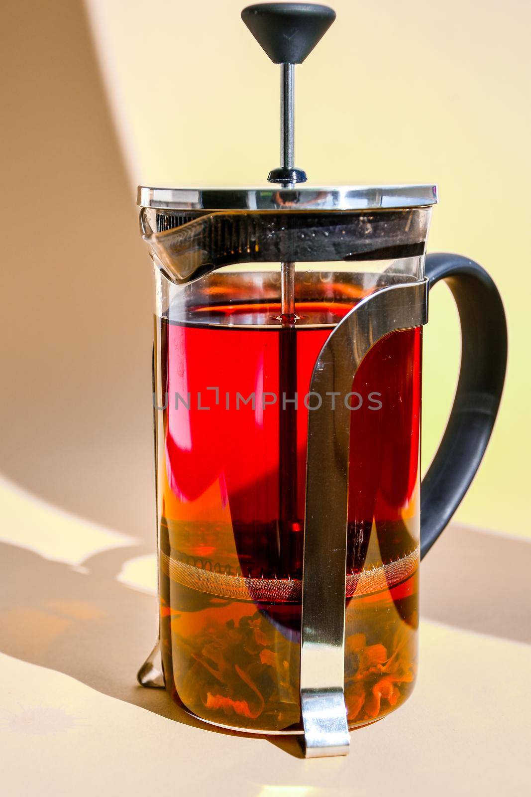 glass teapot with hot hibiscus tea Fresh brewed spicy fruit tea with herbs, rose flowers, hot healthy drink on yellow background with copy space for text by anna_stasiia