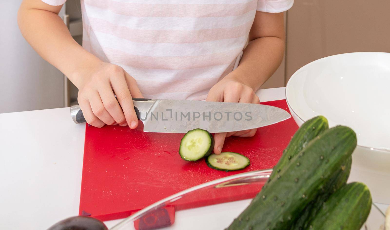 Cropped shot of girl cutting cucumber with knife