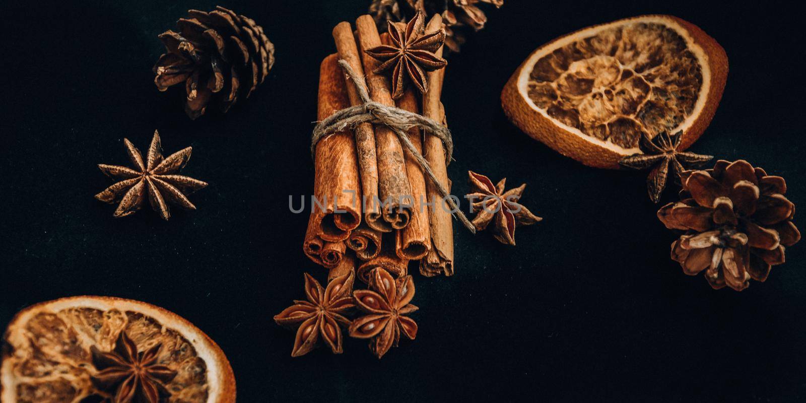 Background of dry slices of orange, cinnamon and star anise, ingredients for preparation mulled wine on black background, Christmas spices