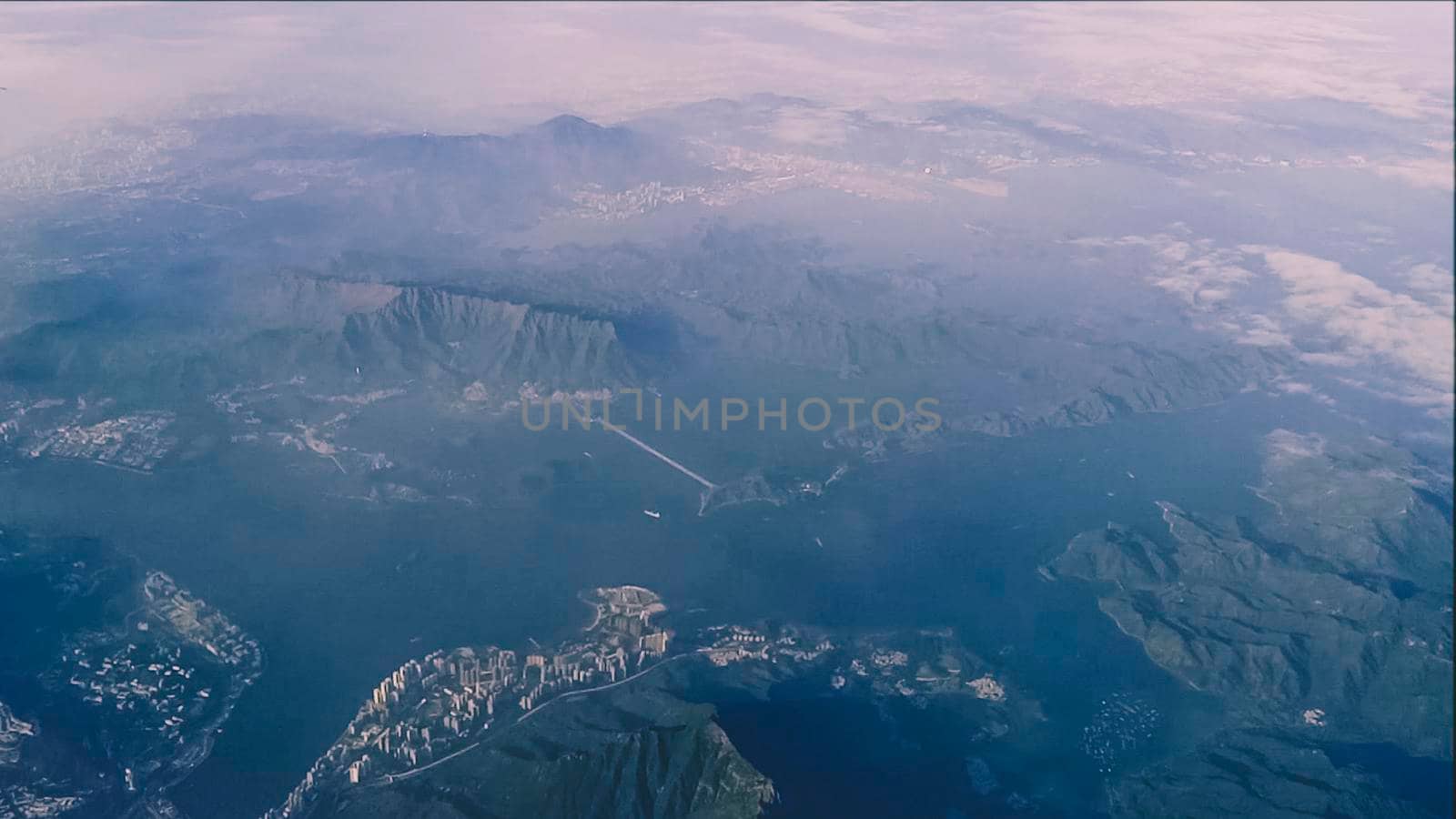 Top aerial view of island mountain clouds from airplane