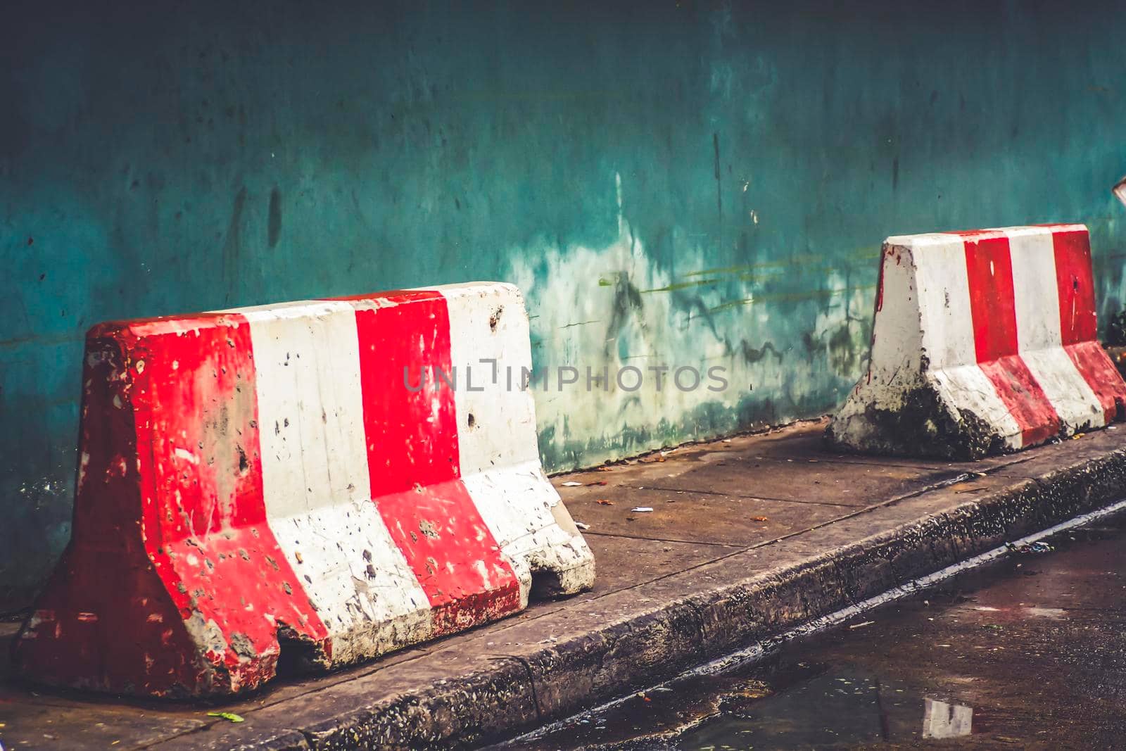 red white concrete barrier stop going sign on street stand on footpath green painted old wall background