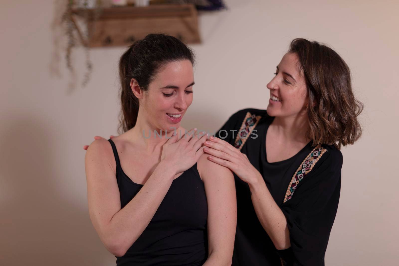 A woman therapist examines her patient's shoulder on the massage table before beginning the chiromassage that will dissipate her back pain