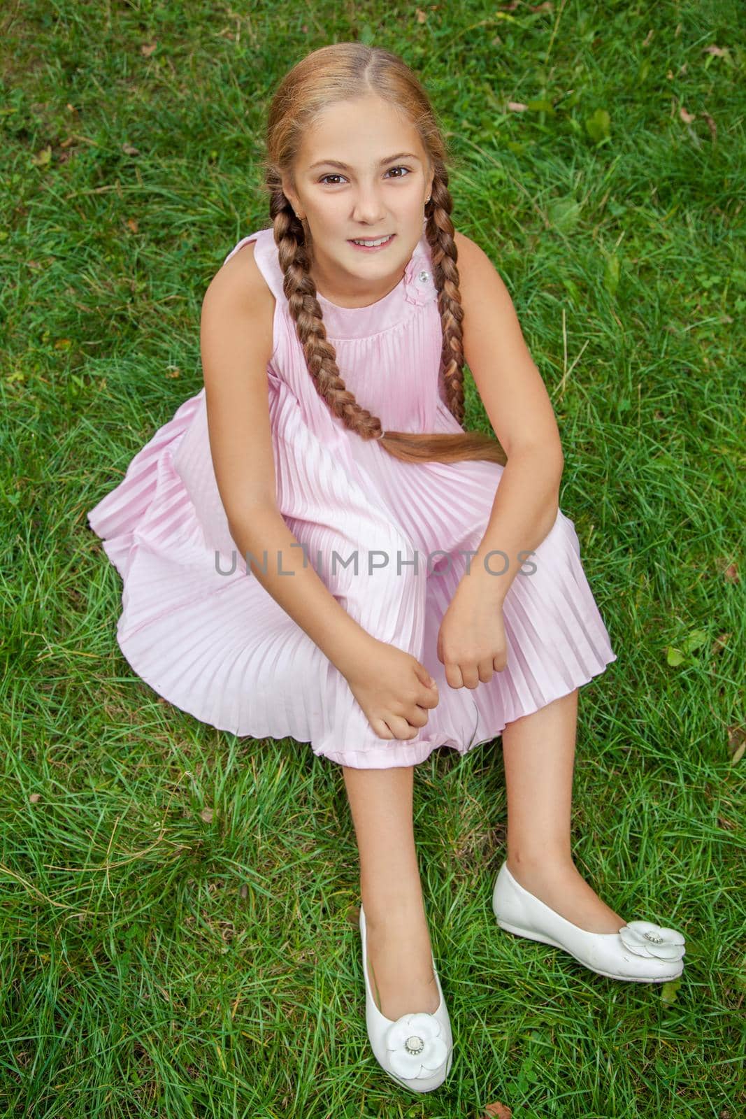 top view portrait of happy girl sitting on lawn and looking at camera with toothy smile by Khosro1