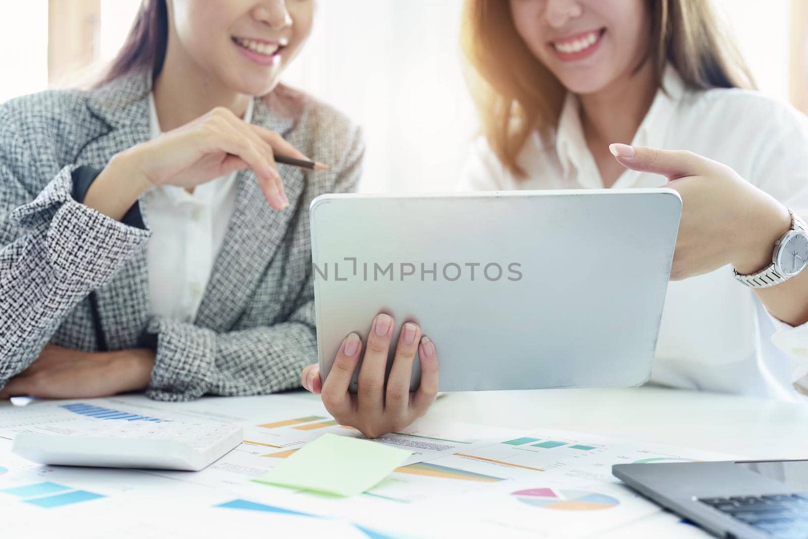 young Asian businesswoman using tablet computers to plan marketing strategies and invest to profit from customers by Manastrong