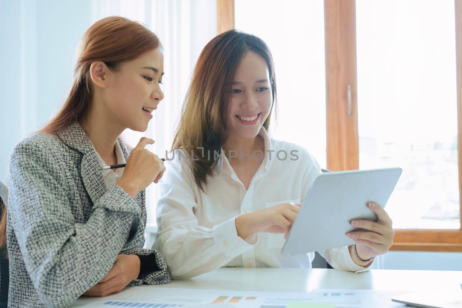 young Asian businesswoman using tablet computers to plan marketing strategies and invest to profit from customers by Manastrong