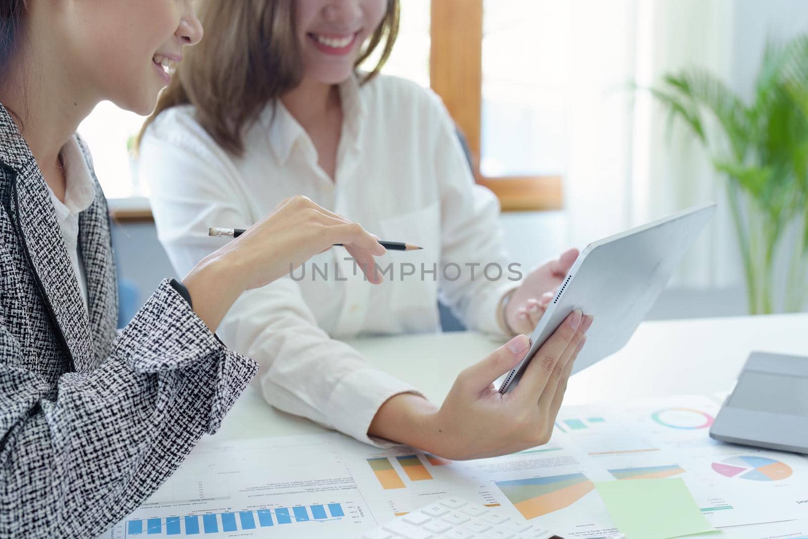 young Asian businesswoman using tablet computers to plan marketing strategies and invest to profit from customers by Manastrong