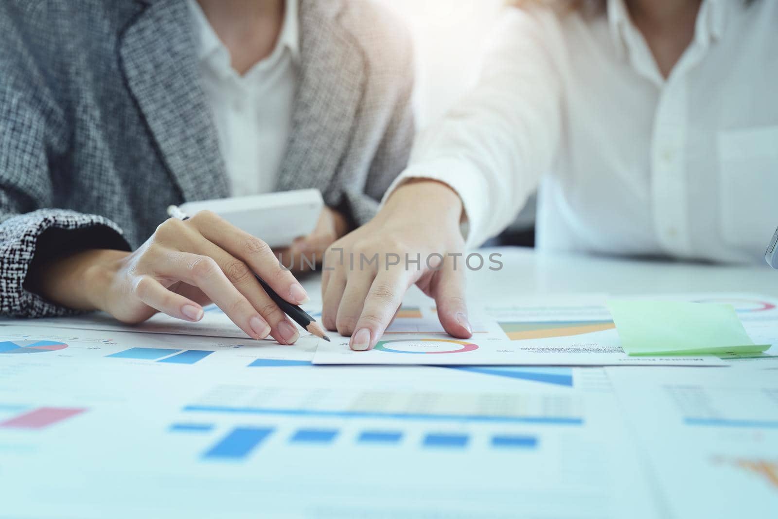 two young Asian businesswoman using their documents to plan marketing strategies and investments to profit from their clients by Manastrong
