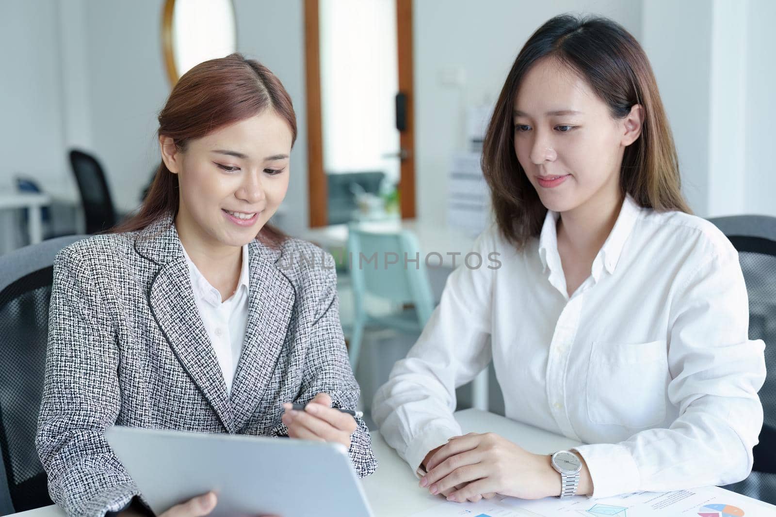 young Asian businesswoman using tablet computers to plan marketing strategies and invest to profit from customers by Manastrong