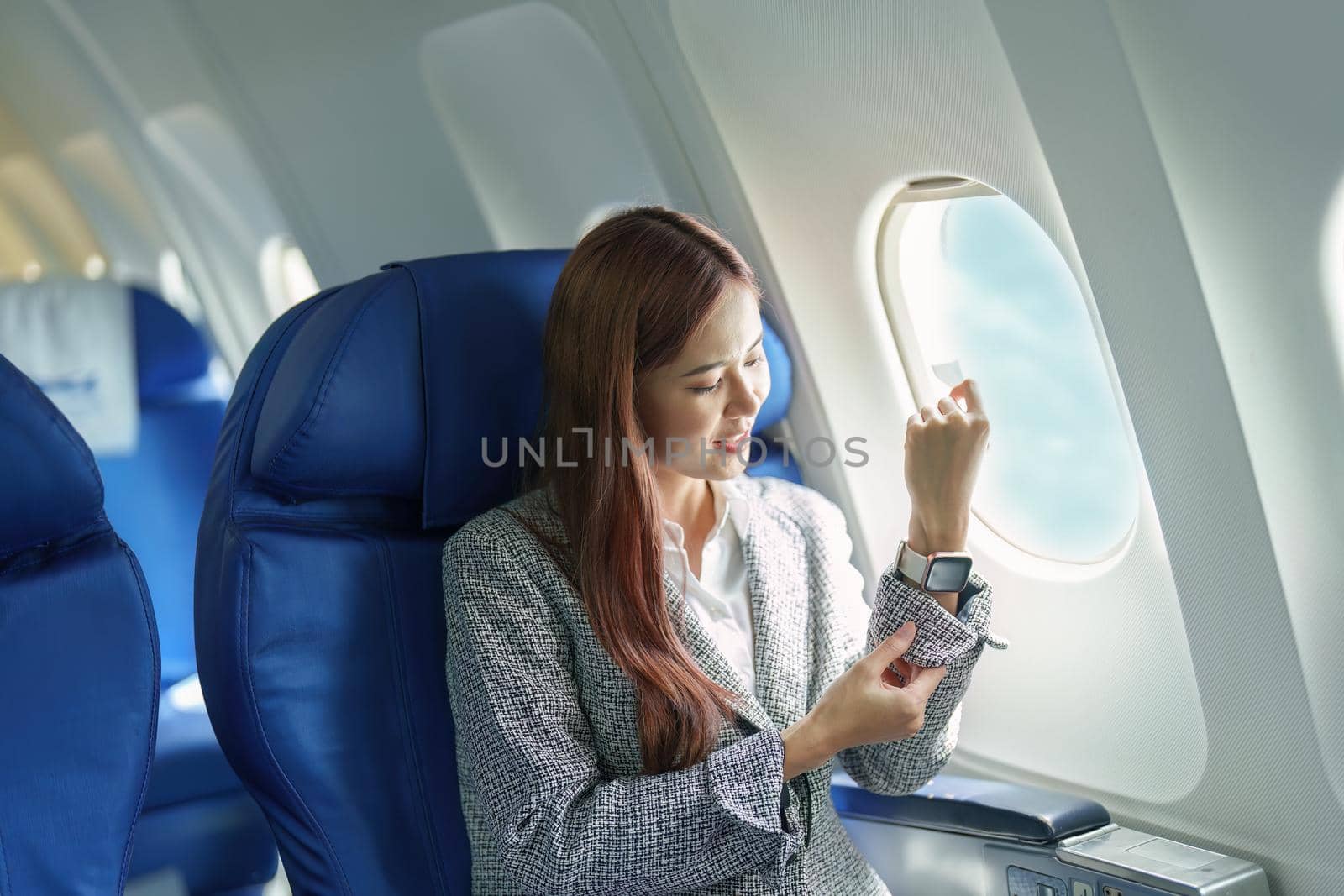 Portrait of a young Asian businesswoman smiling while riding a plane.