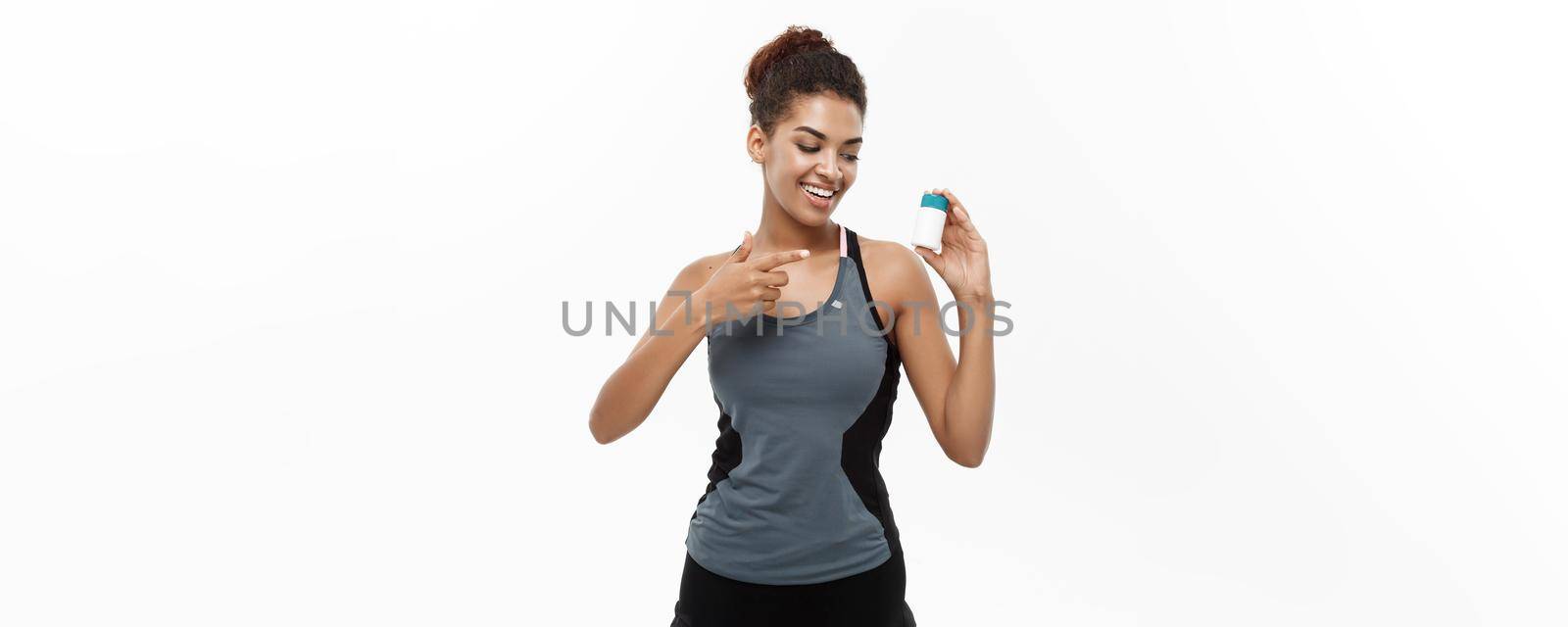 Healthy and healthcare concept - portrait of beautiful sporty African American holding bottle of supplementary bottle. Isolated on white studio background