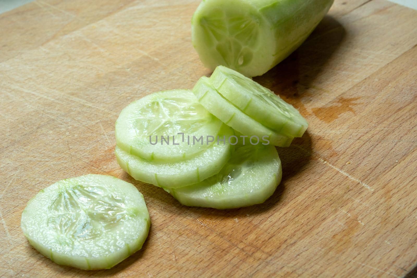 Peeled and sliced cucumber lies on a board, close up