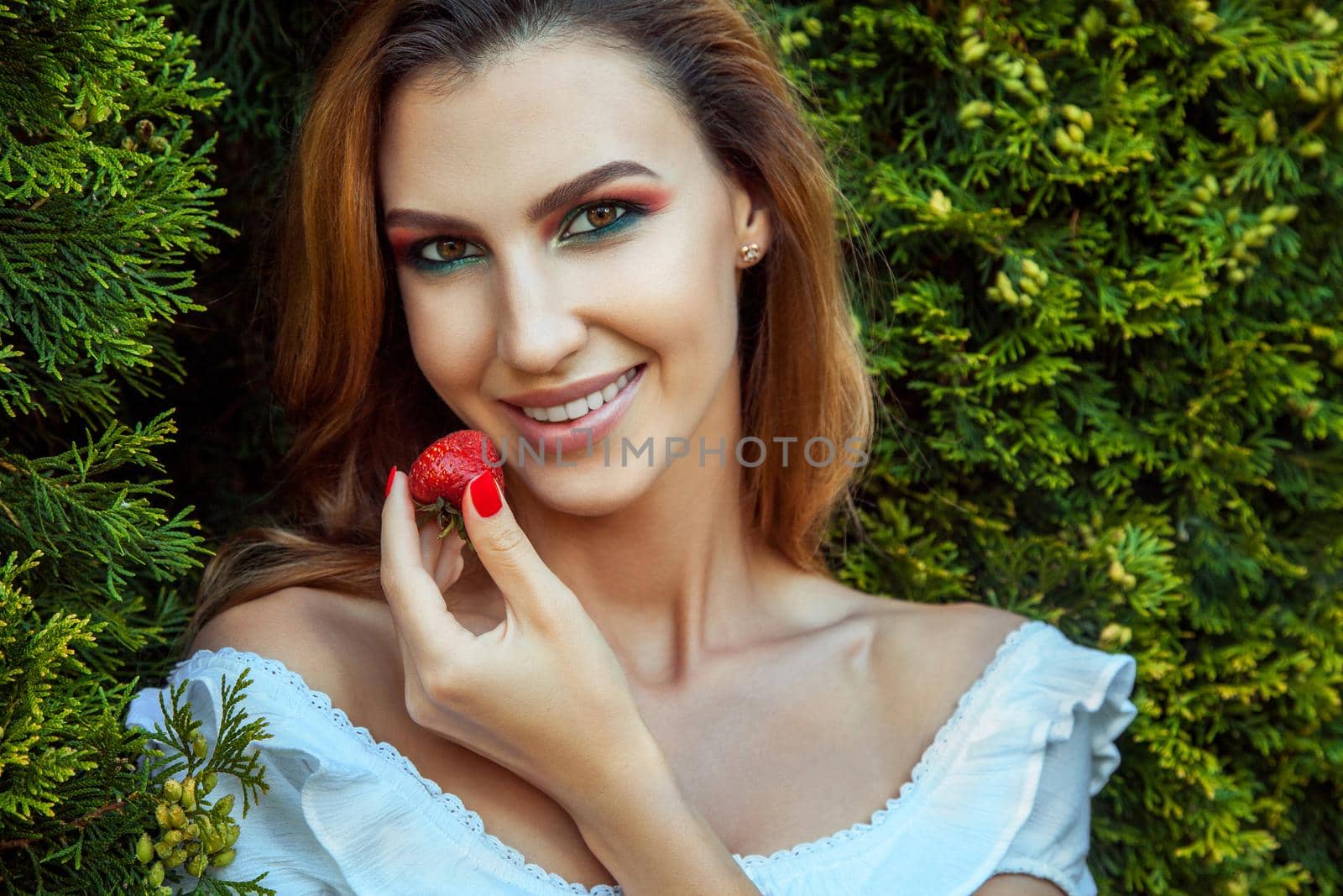 Healthy food concept. Happiness model holding strawberry and toothy smiling. Outdoor spring or summer photo