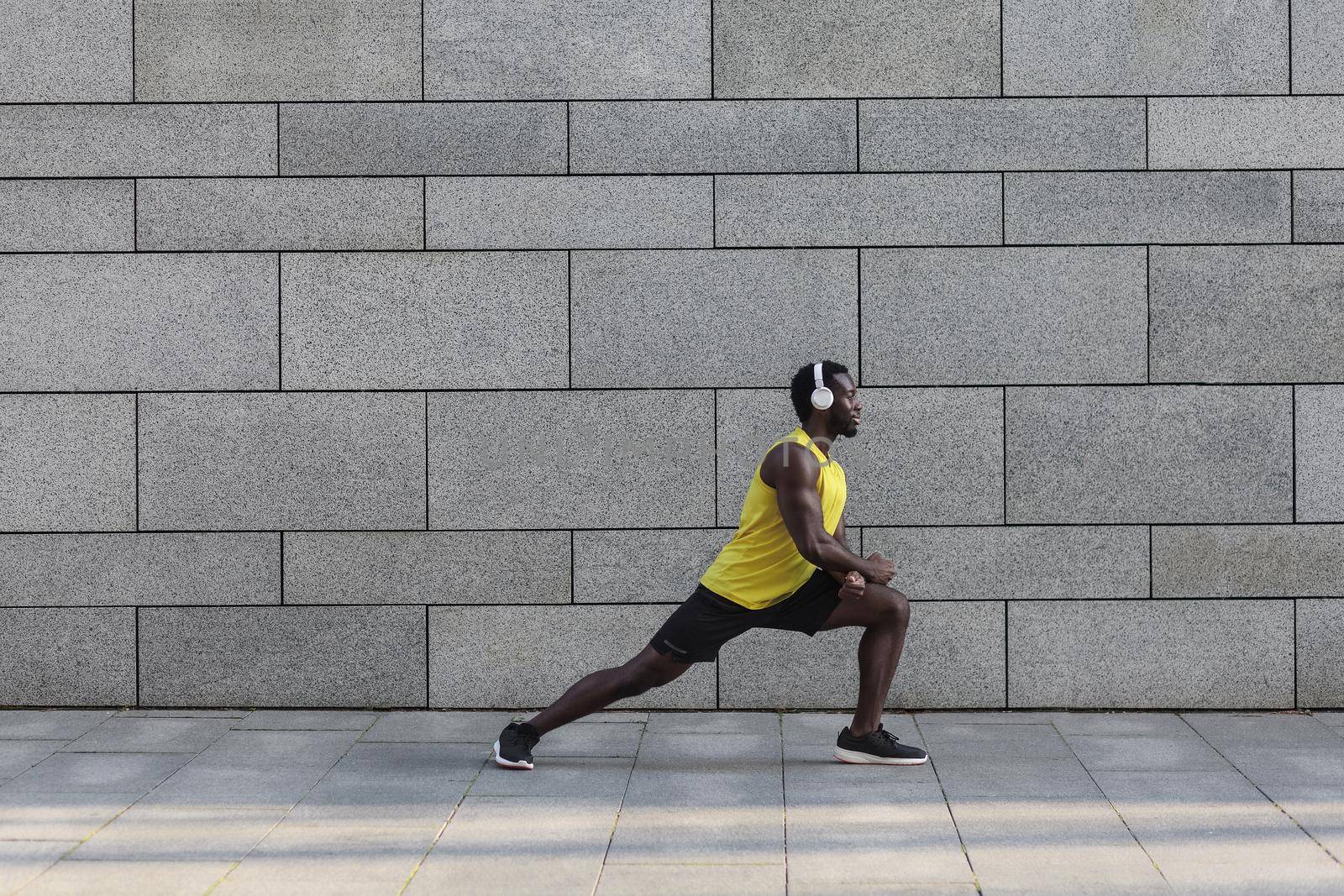 Fitness and health concept. Afro american jogger doing stretching after morning workout.