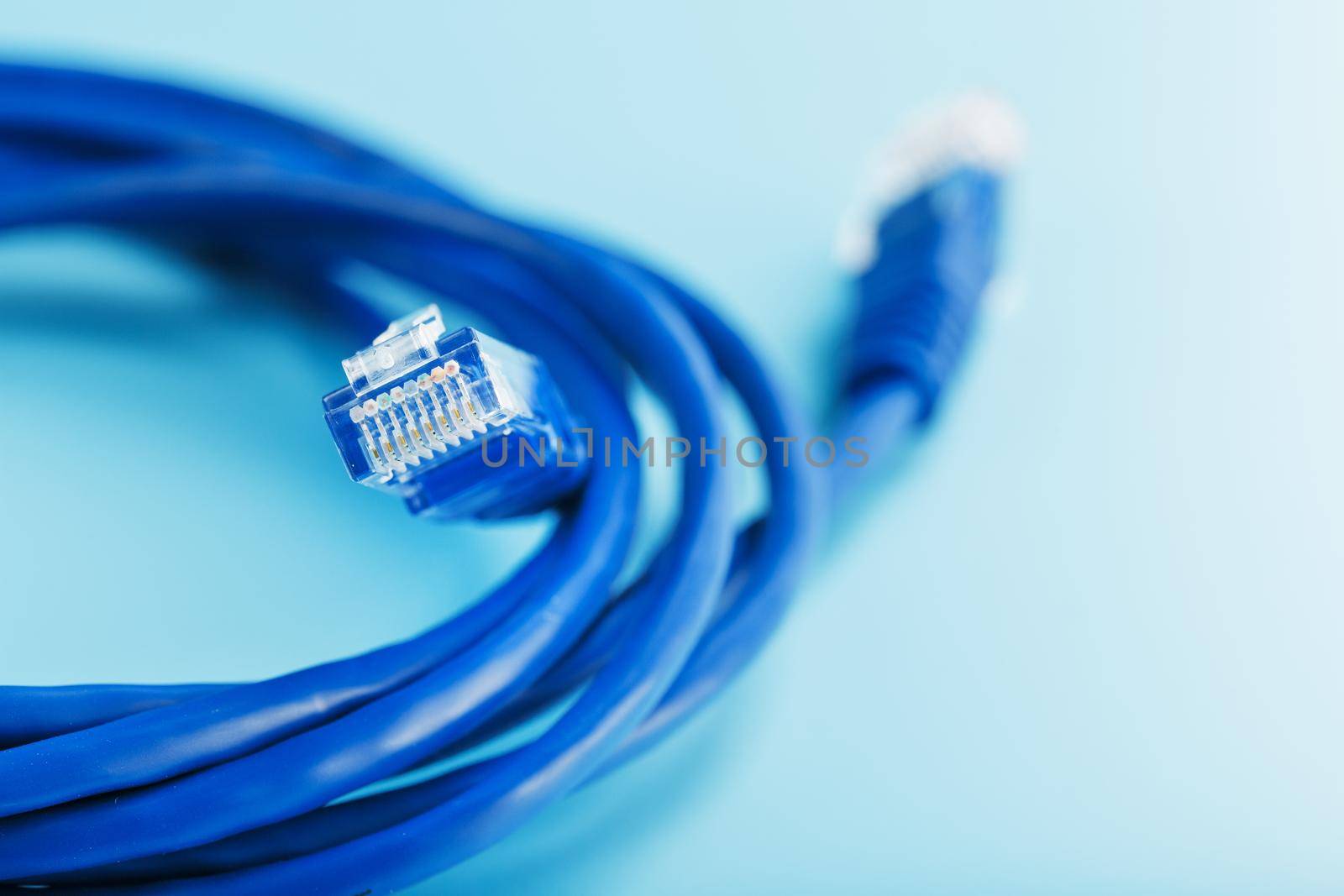 Blue Ethernet Cable Connectors Patch cord cord close-up isolated on a blue background with free space