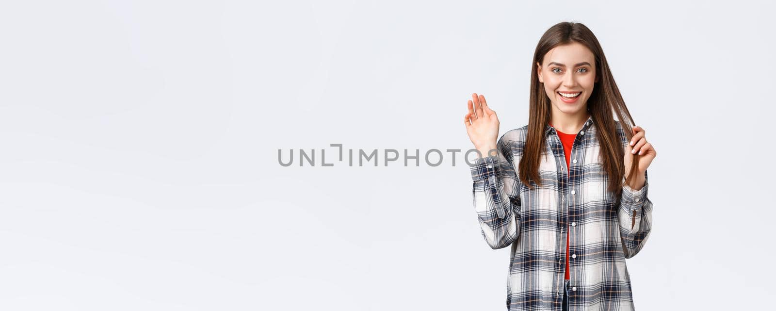 Lifestyle, different emotions, leisure activities concept. Friendly attractive young woman saying hi or bye, waving hand in greeting with happy enthusiastic smile, meeting fellow students.